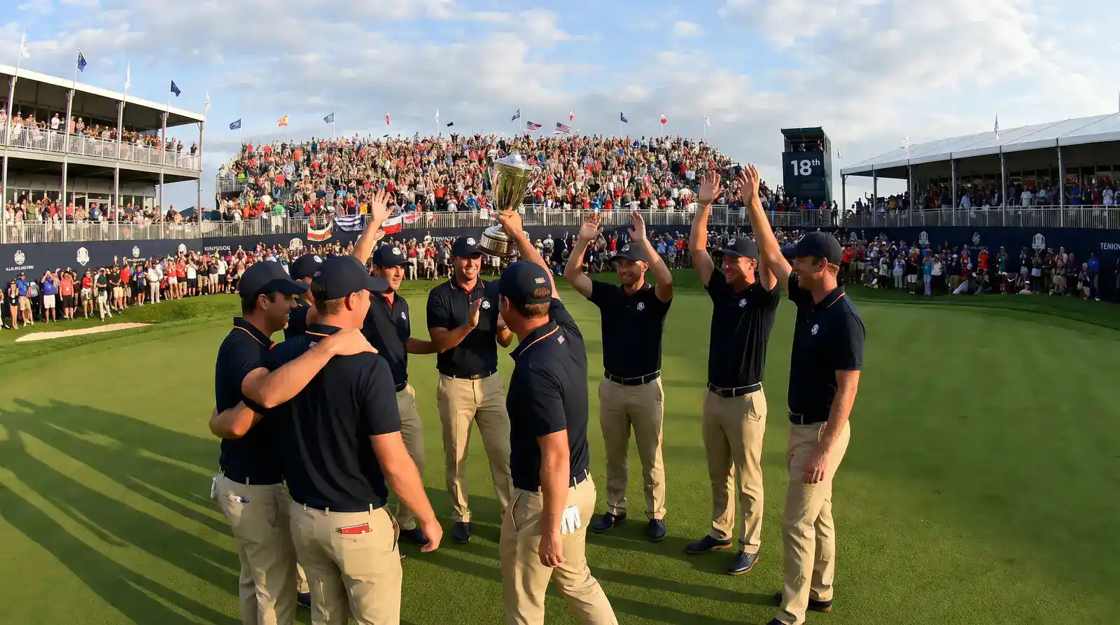 Golf team players celebrating a Ryder Cup victory on the 18th green with crowd cheering